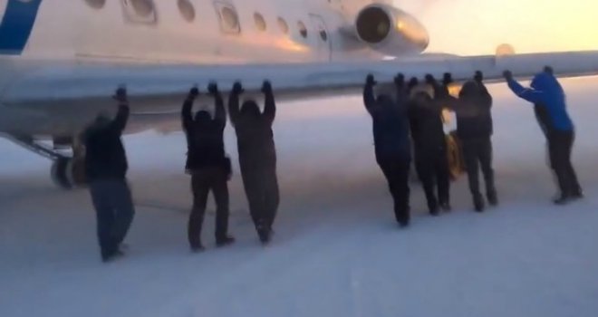 Putnici guraju avion koji ne može krenuti zbog niskih temperatura